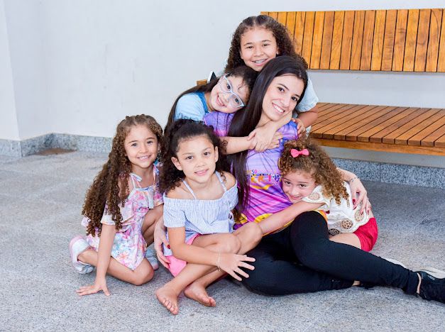 Uma recreadora abraçada com várias meninas, todas sorridentes